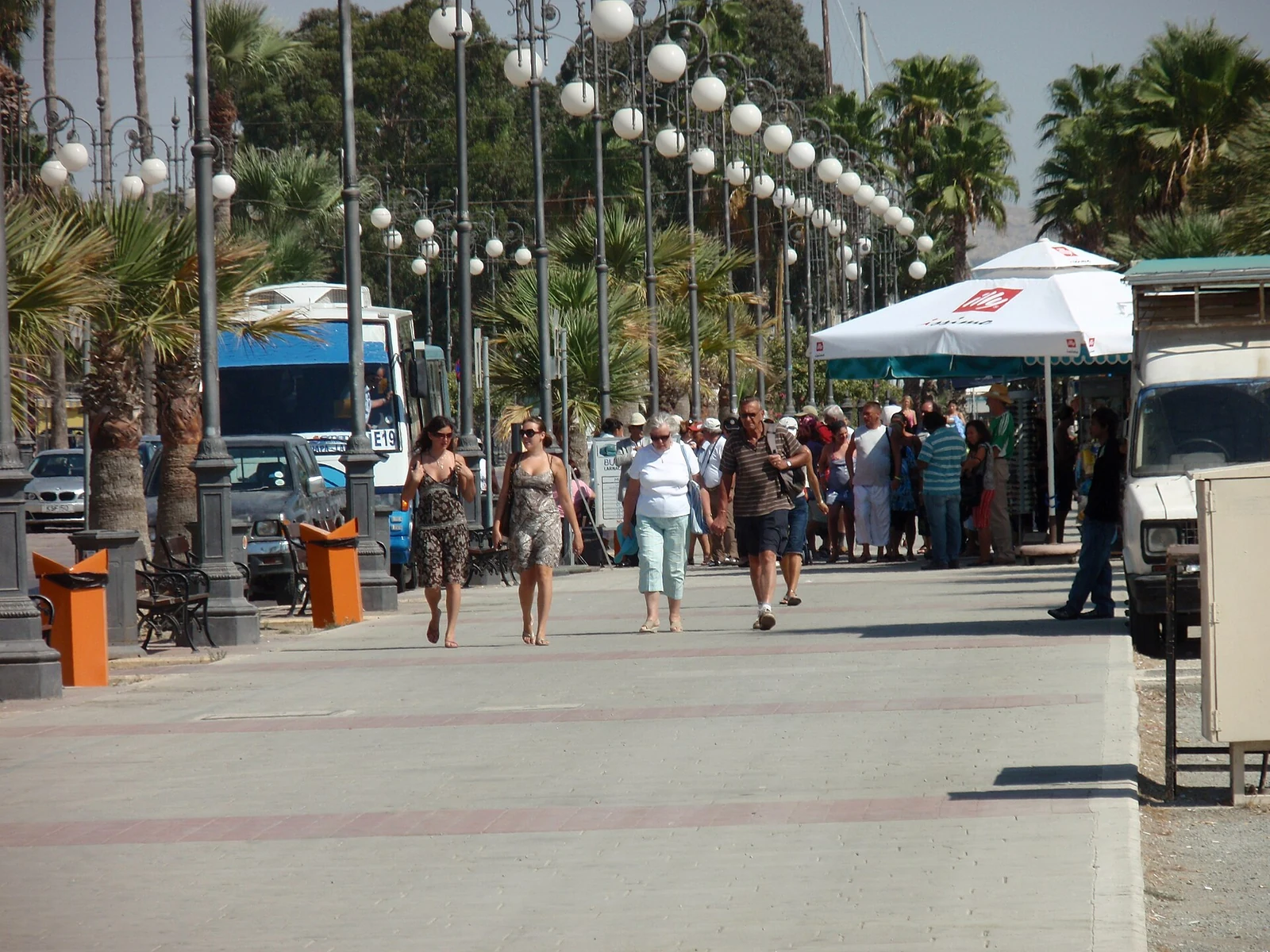 Piesi i palmy na promenadzie Finikoudes w Larnace