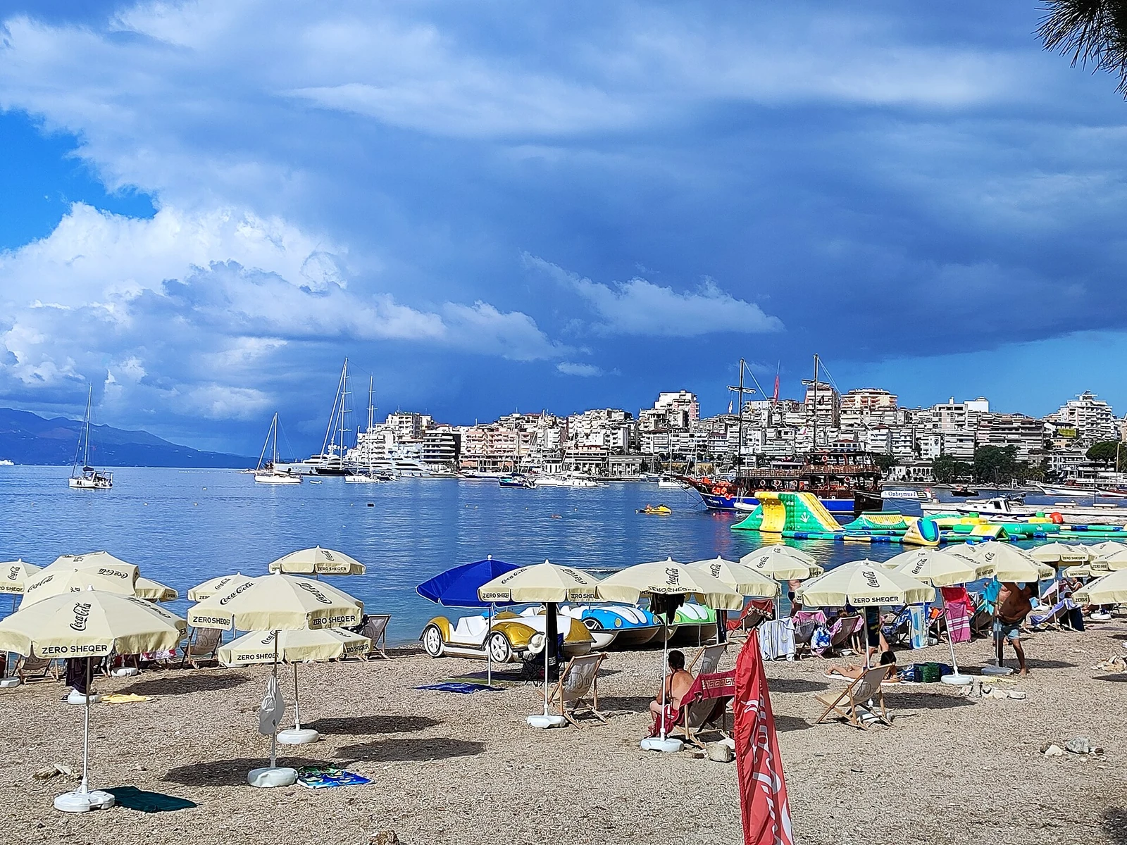 Plaża publiczna z parasolami i widokiem na zabudowę Sarandy