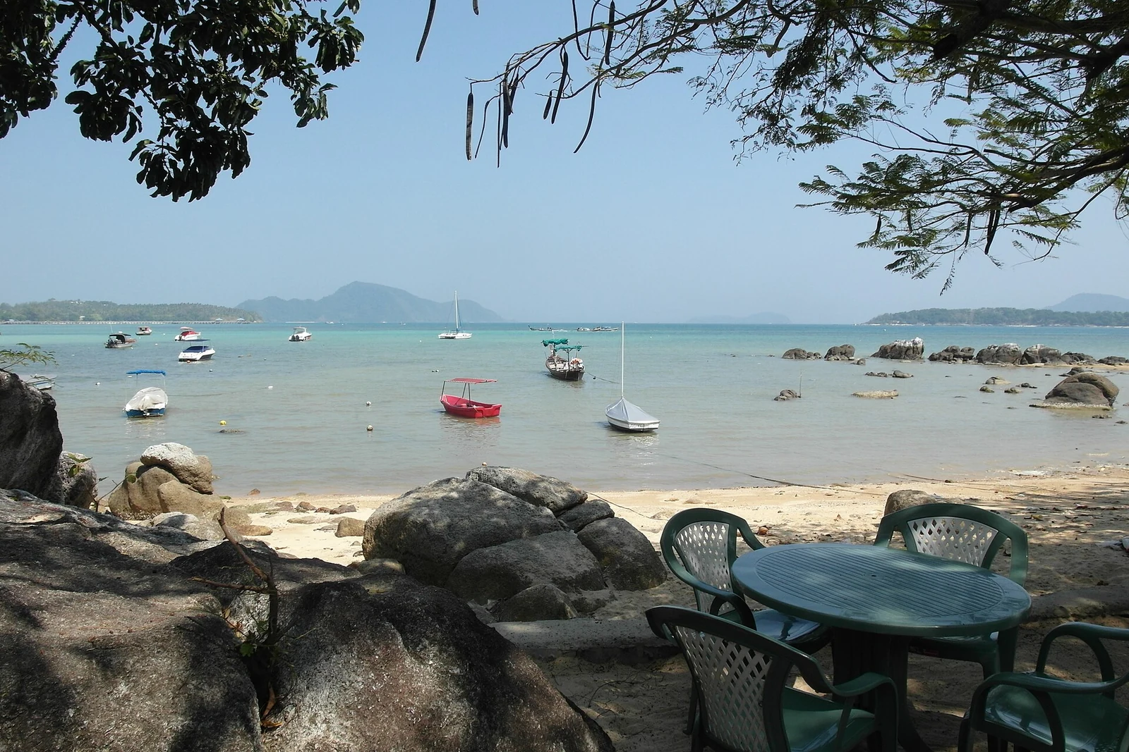 Łodzie przy brzegu Rawai oglądane spod drzew na Phuket