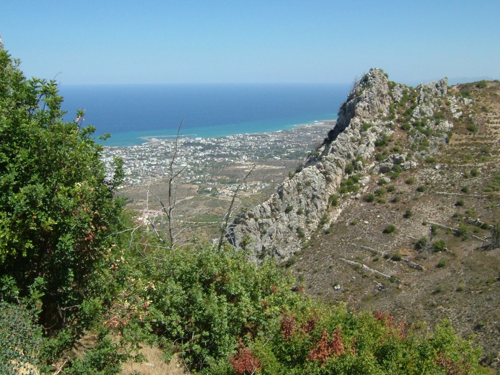 Skalisty stok i zabudowa Kyrenii nad morzem widziane z St Hilarion