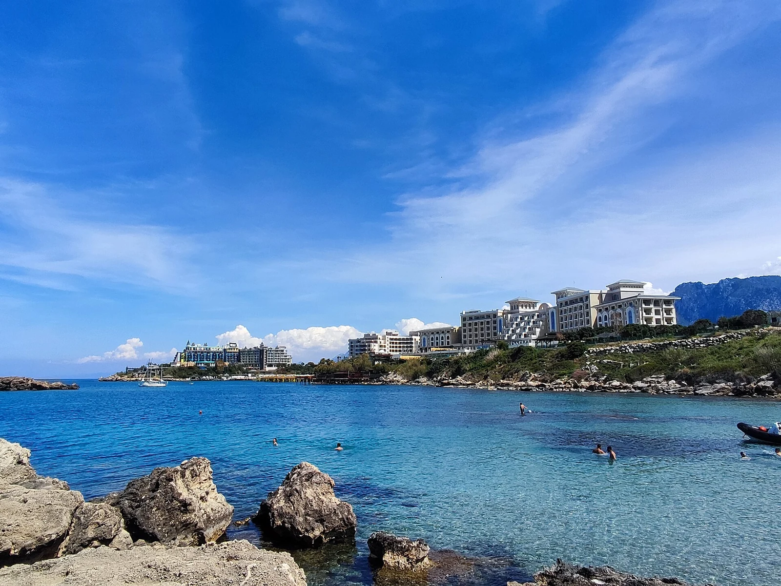 Skalisty brzeg, woda i zabudowa przy plaży Mare Monte