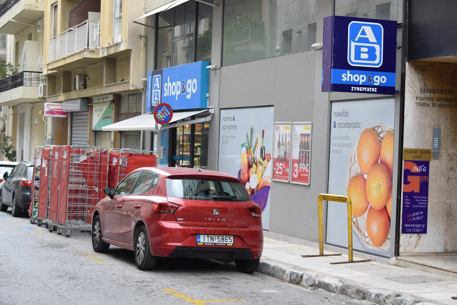 Sklep AB shop&go przy ulicy w Kolonaki, z balkonami budynku i zaparkowanym samochodem