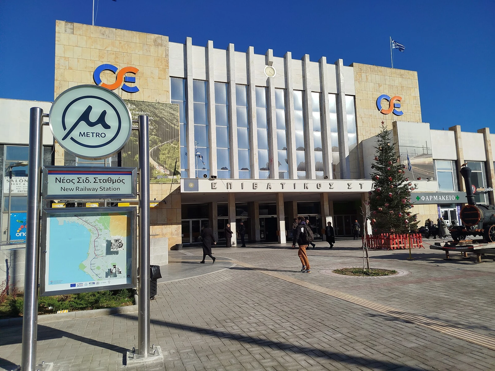 Tablica metra New Railway Station przed fasadą dworca kolejowego w Salonikach