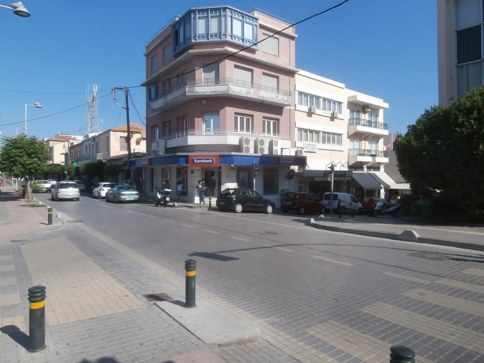 Narożny budynek z balkonami, lokale w parterze i samochody na skrzyżowaniu Kountourioti Pavlou oraz Dimokratias w Rethymno