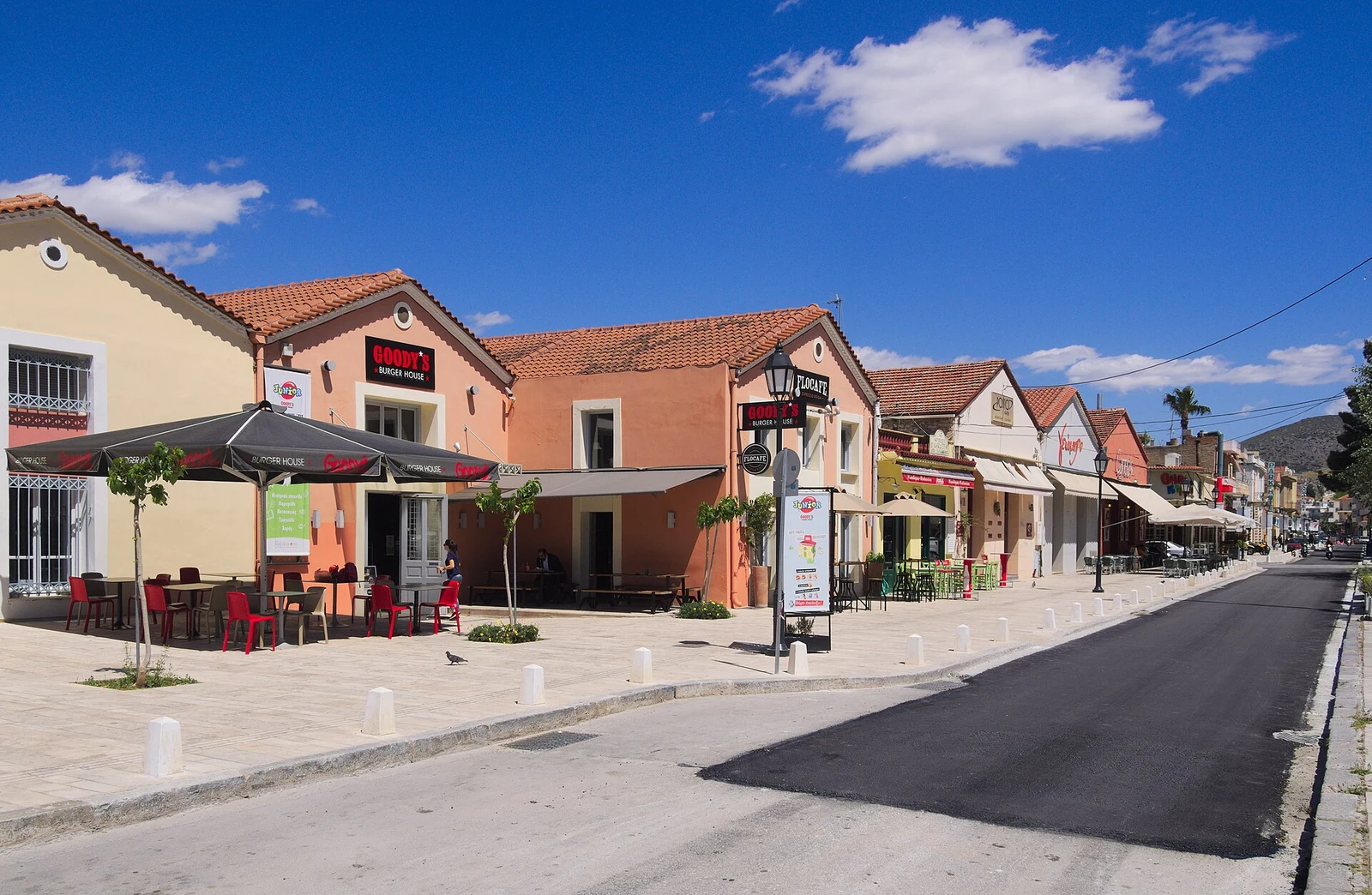 Niskie kolorowe budynki z lokalami gastronomicznymi i stolikami przy ulicy Sidiras Merarchias w Nafplio