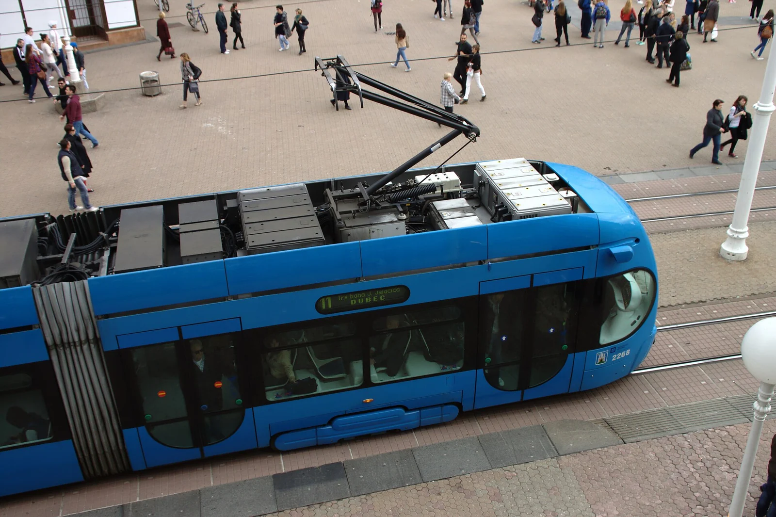 Niebieski tramwaj TMK 2200 i piesi na placu bana Jelačicia w Zagrzebiu