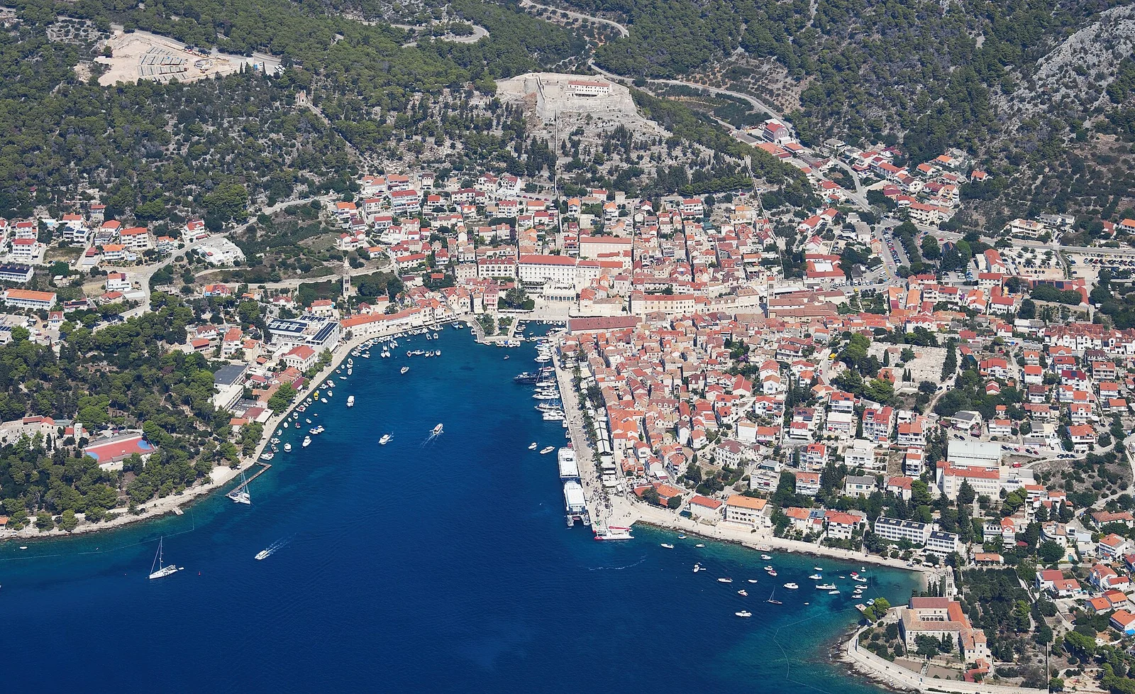 Lotniczy widok miasta Hvar od południa, z portem i zabudową na zboczach