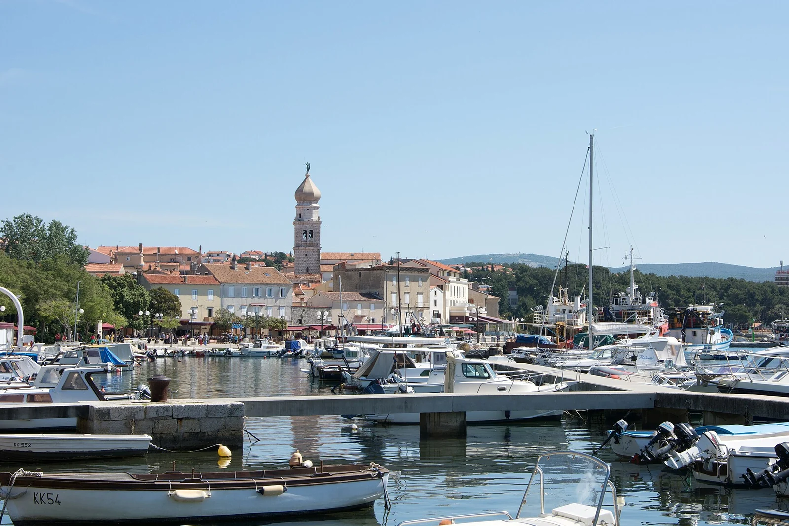Port miasta Krk z łodziami, wieżą i zabudową przy nabrzeżu